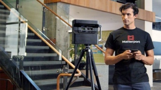 A Capture Services Technician with a Pro2 camera in a building with stairs in the background